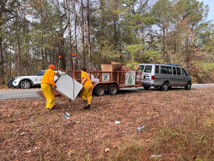 Neshoba County Detention Center inmates haul off an old appliance as they work to pick up trash in the county.